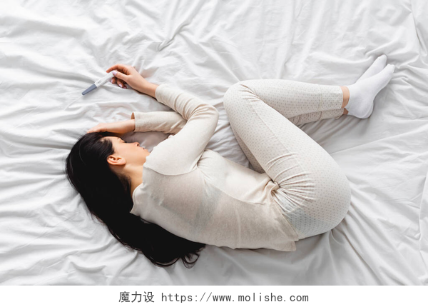 拿着验孕棒睡在床上的美女接近妊娠期时躺在床上的抑郁妇女的头像测试结果为阴性 